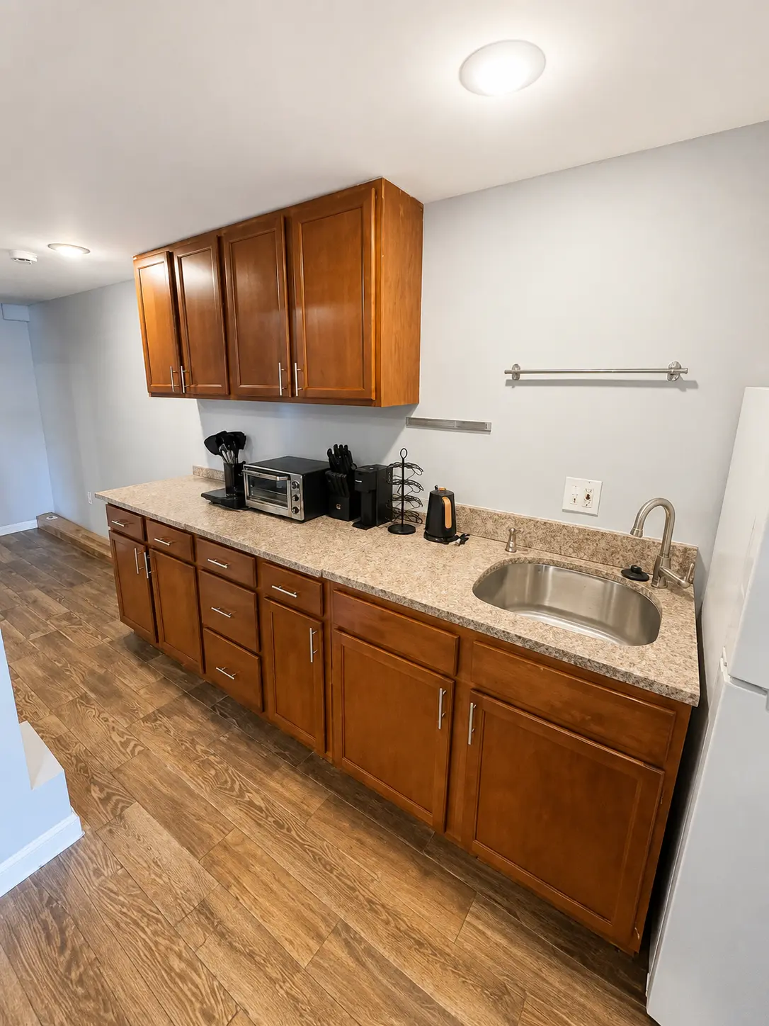 Studio kitchenette with wood cabinetry, sink, and small appliances